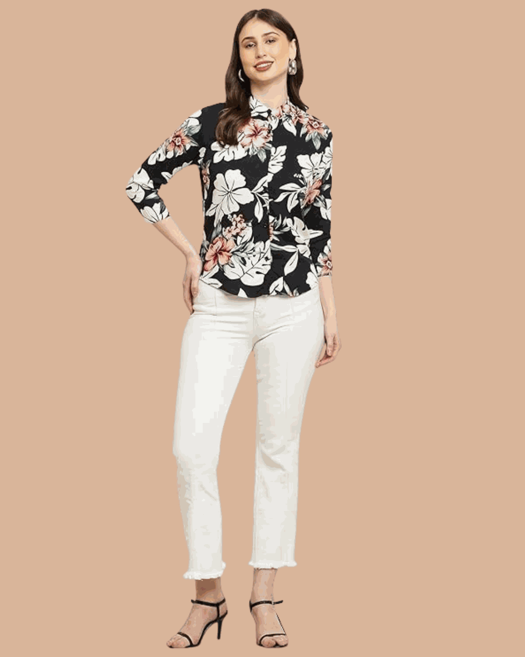Woman wearing a black floral women's rayon viscose shirt with white pants and black heels against a beige background.