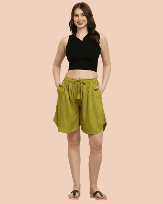 Woman wearing olive green rayon print culotte shorts with a black sleeveless crop top and sandals.